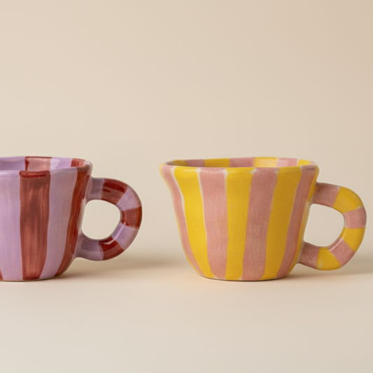 Two ceramic mugs with striped patterns on a beige background