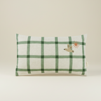 Green checkered pillow with a bird design on a beige background