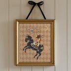 Framed artwork of a cowboy riding a horse with a decorative pattern on a wall.