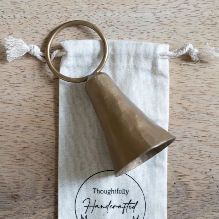 Bell shaped candle snuffer laying on a cloth bag with a drawstring.
