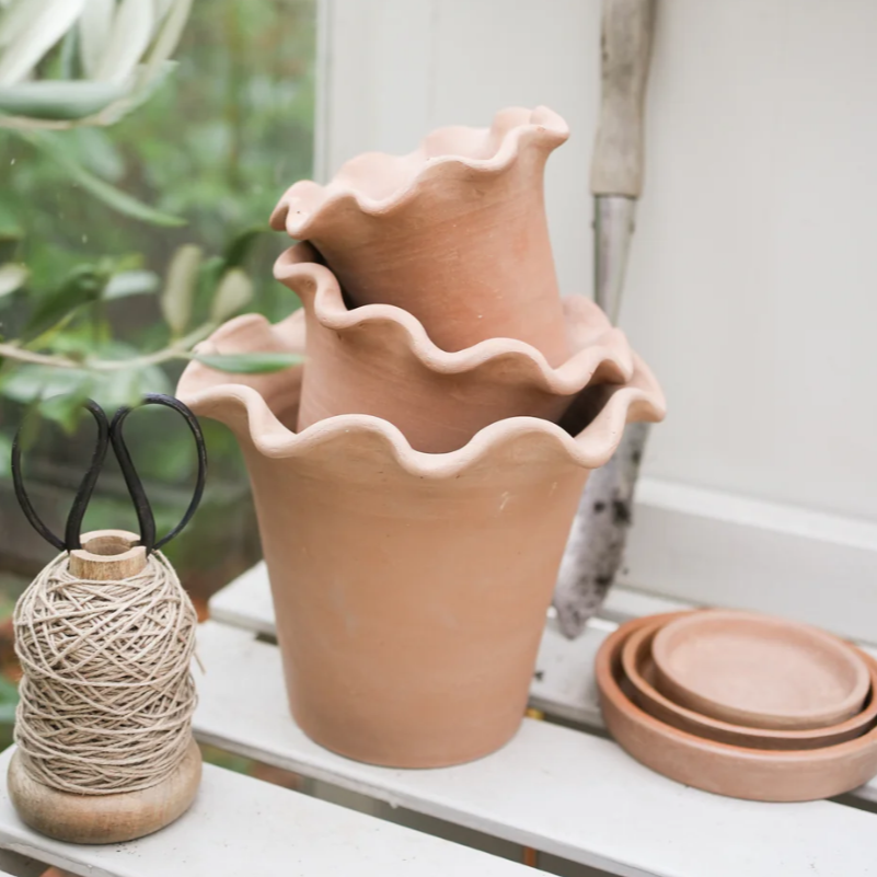 Frilly plant pots available in three sizes displayed stacked on top of each other in a greenhouse setting