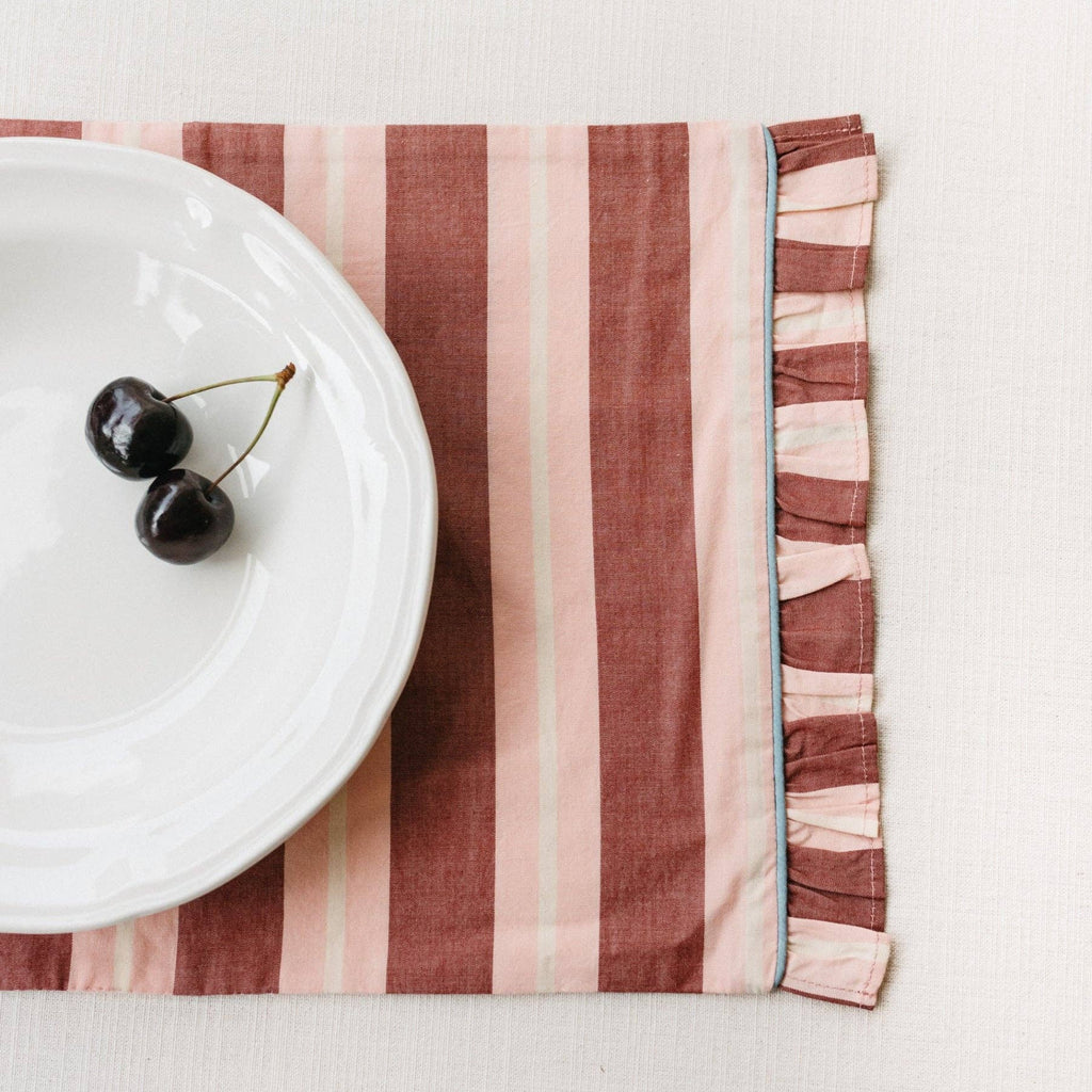 Pink and Red stripe cotton placemat displayed with a white plate with 2 cherries placed on top.