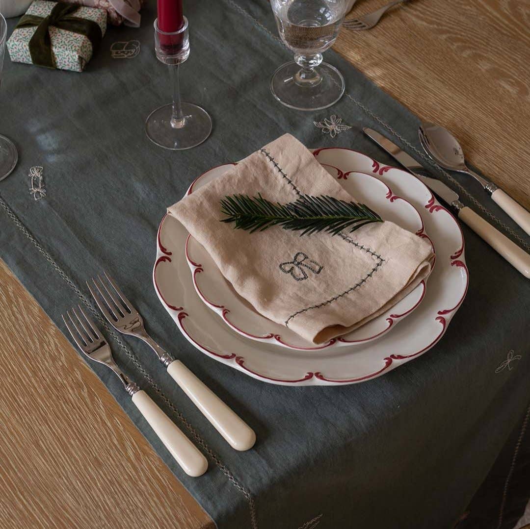 Dining table setting with plates, napkin, and cutlery on a dark tablecloth.