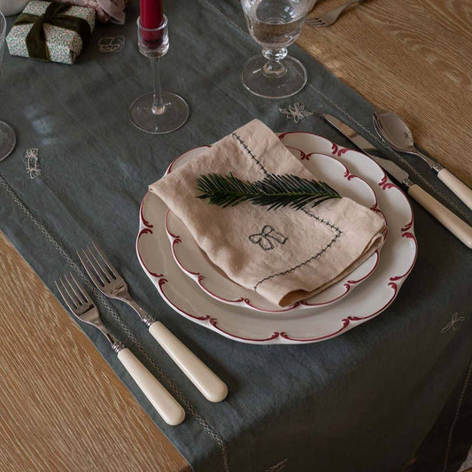 Dining table setting with plates, napkin, and cutlery on a dark tablecloth.