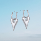 Silver heart-shaped hoop earrings on a light blue background