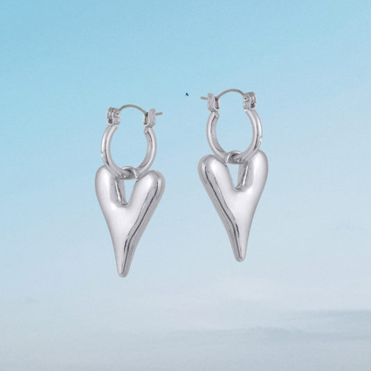 Silver heart-shaped hoop earrings on a light blue background