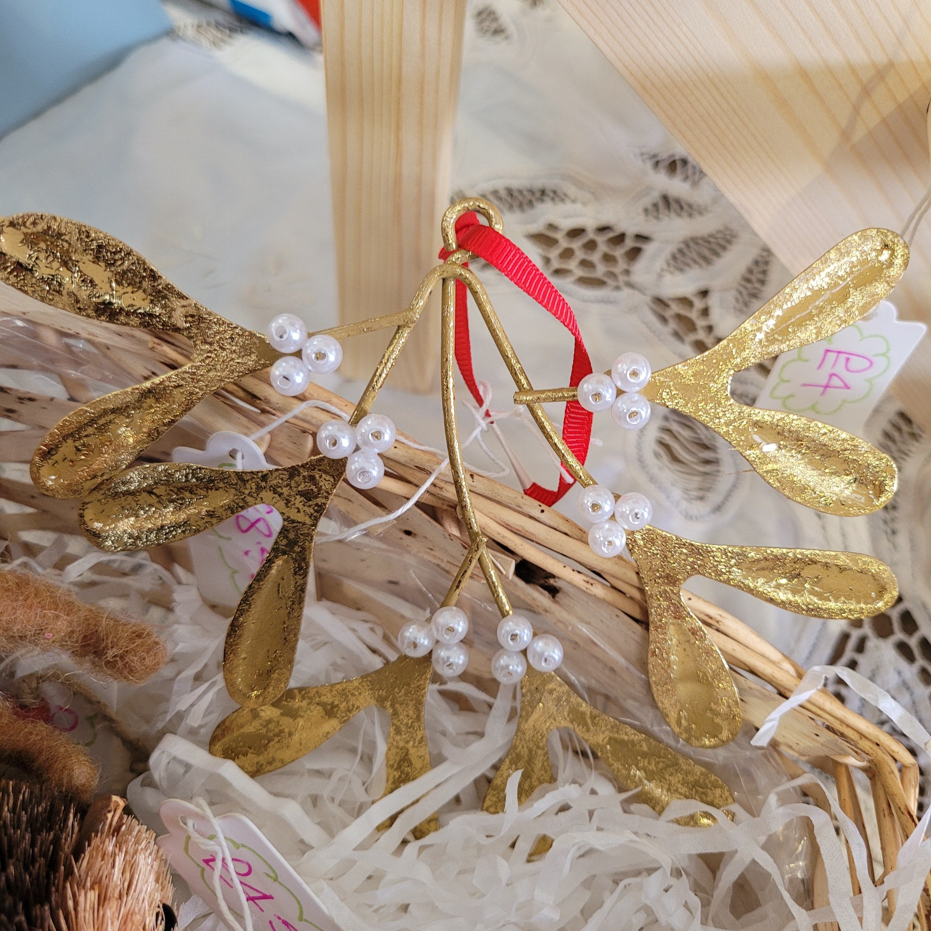 A festive gold-colored Christmas ornament with intricate brass details and small white pearls, designed to resemble mistletoe.
