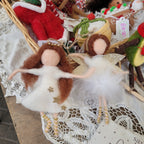 Two angel figurines with brown hair and white dresses, one with gold wings and the other with silver wings, both adorned with polka dots and stars.