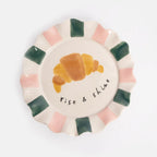 Decorative plate with a croissant illustration and 'Rise & Shine' text on a white background