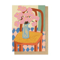 Card with a design of a chair with a vase of pink flowers on a patterned background