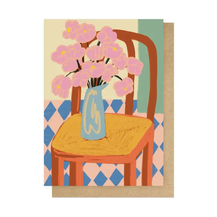 Card with a design of a chair with a vase of pink flowers on a patterned background