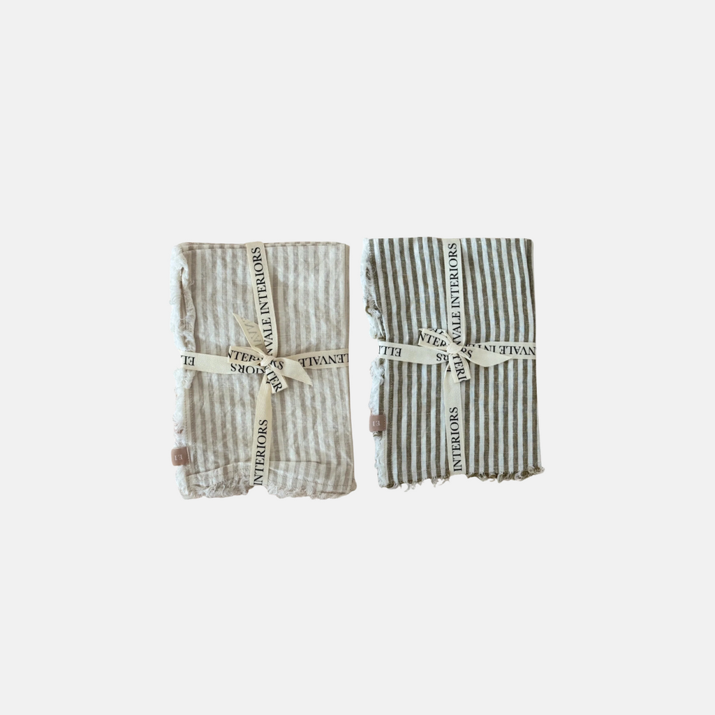 Two folded striped linen napkins with a ruffled edge with text on a white background