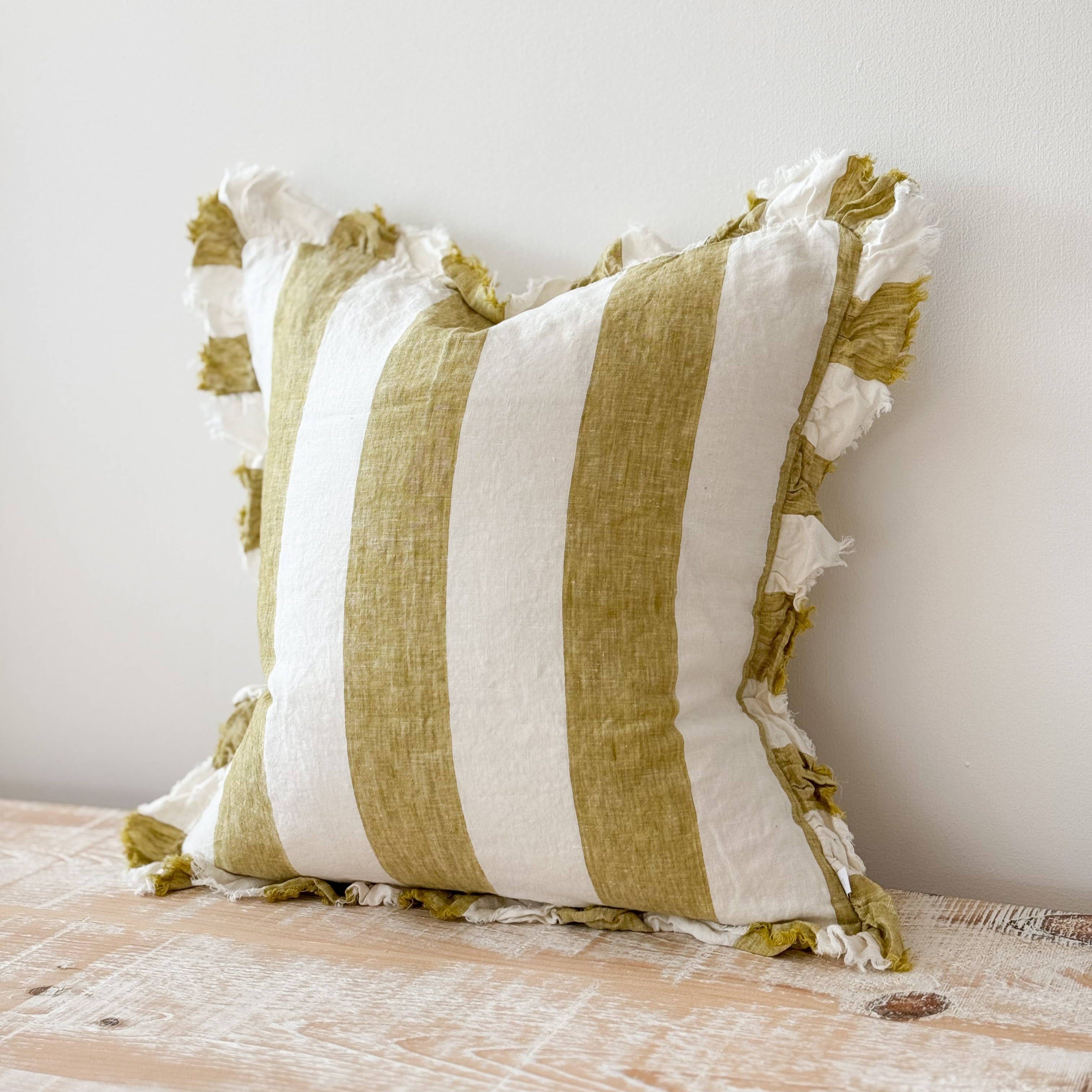 Striped pillow with tassels on a wooden surface