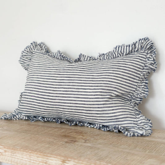 Striped pillow with ruffled edges on a wooden surface against a white background