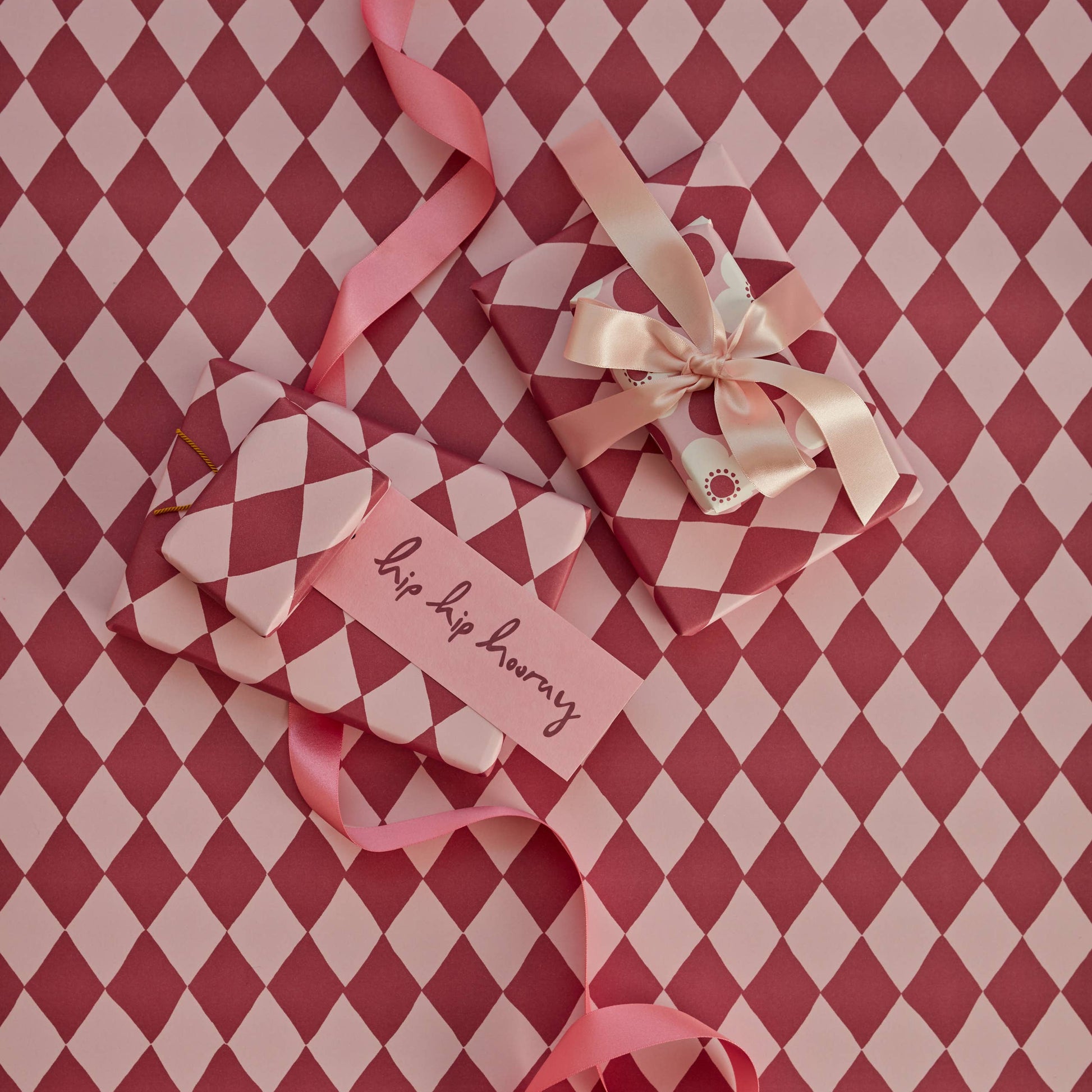 Heart-shaped gift with ribbons and a tag on a red and white checkered background