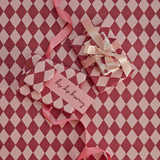 Heart-shaped gift with ribbons and a tag on a red and white checkered background