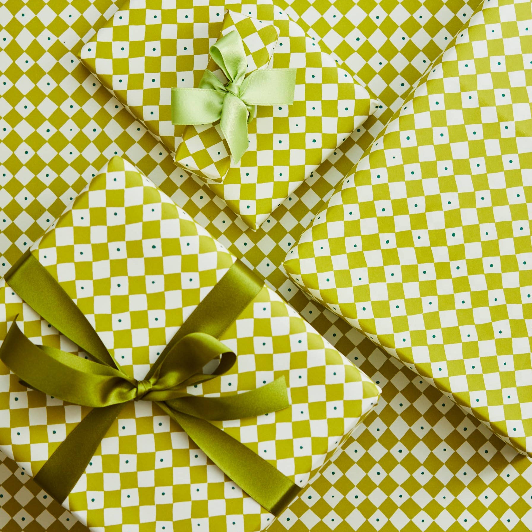 Three gift boxes with green ribbons on a green and white checkered background
