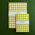 Two green patterned notebooks on a green background