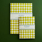 Two green patterned notebooks on a green background