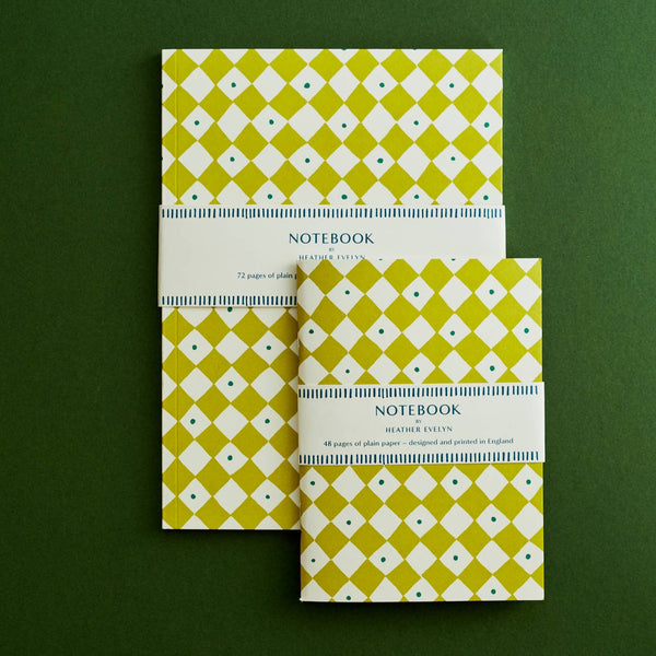 Two green patterned notebooks on a green background