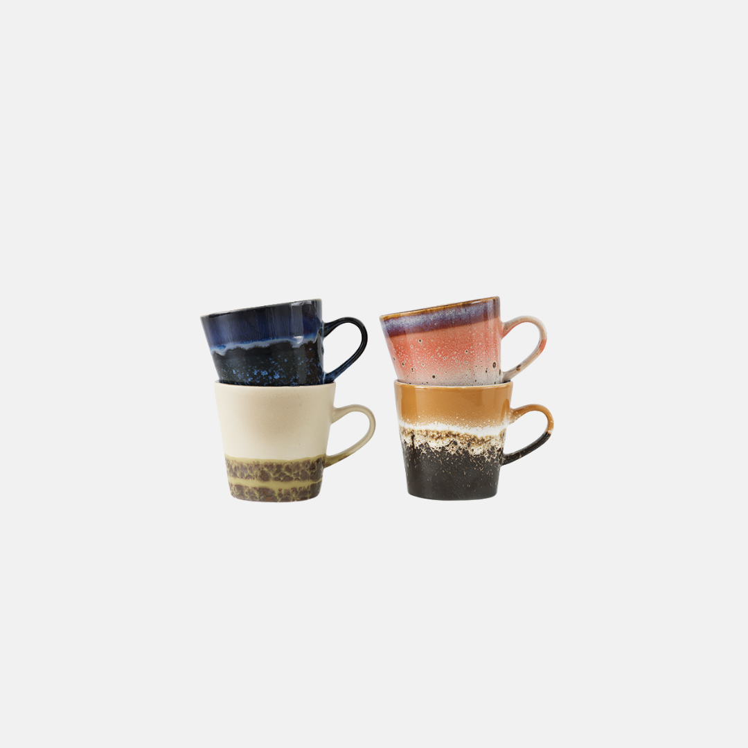 Two stacked ceramic mugs with a rustic hand-painted finish, one in navy blue, cream, and brown, and the other in pink, brown, and black, set against a plain light gray background.