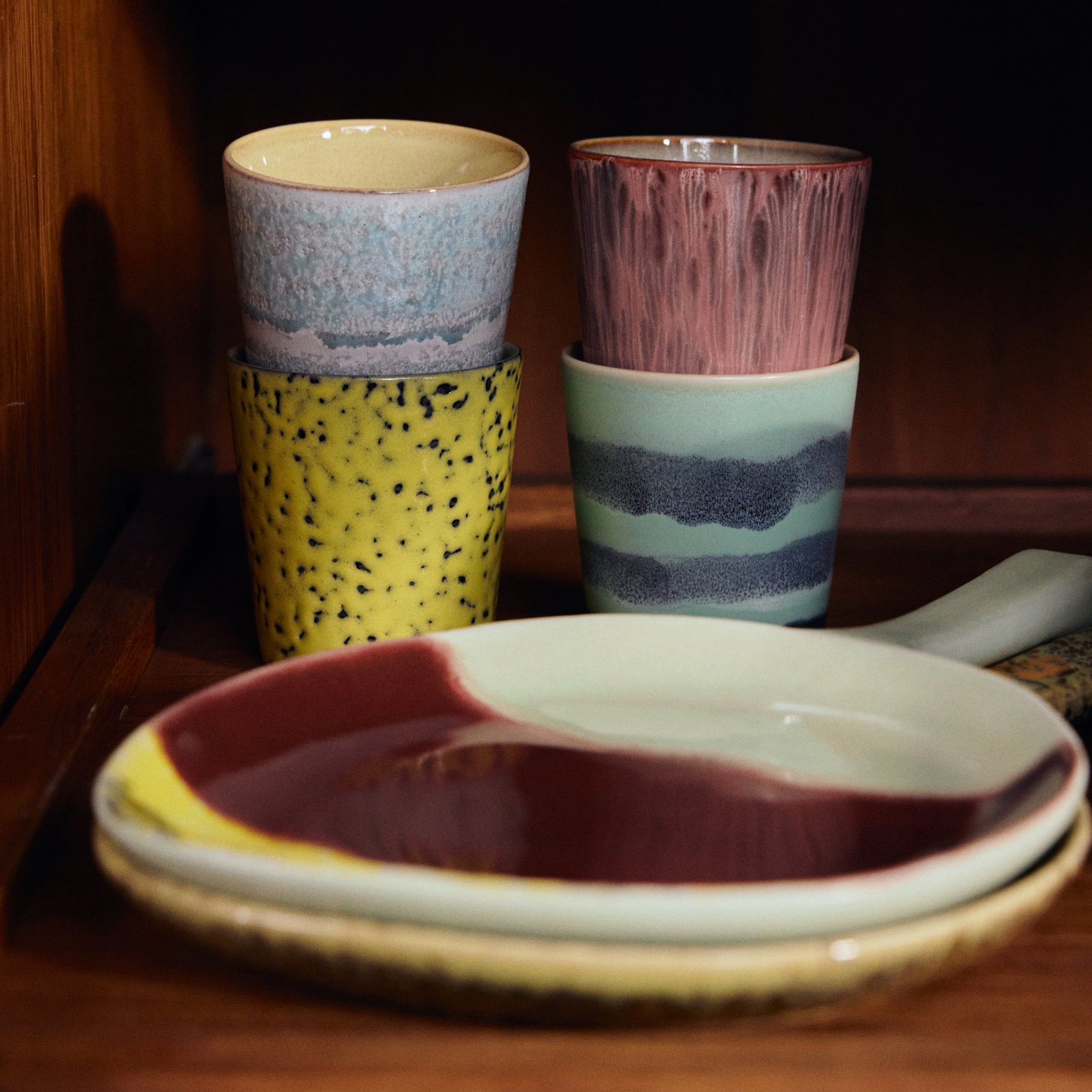 Four ceramic cups with different patterns on a wooden surface