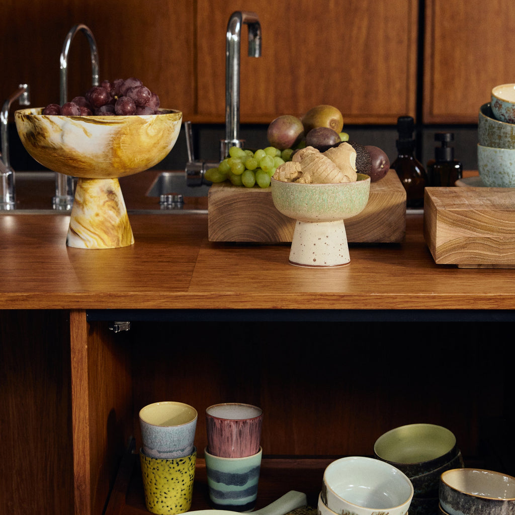 Kitchen counter with ceramic bowls, fruit, and wooden cabinets.