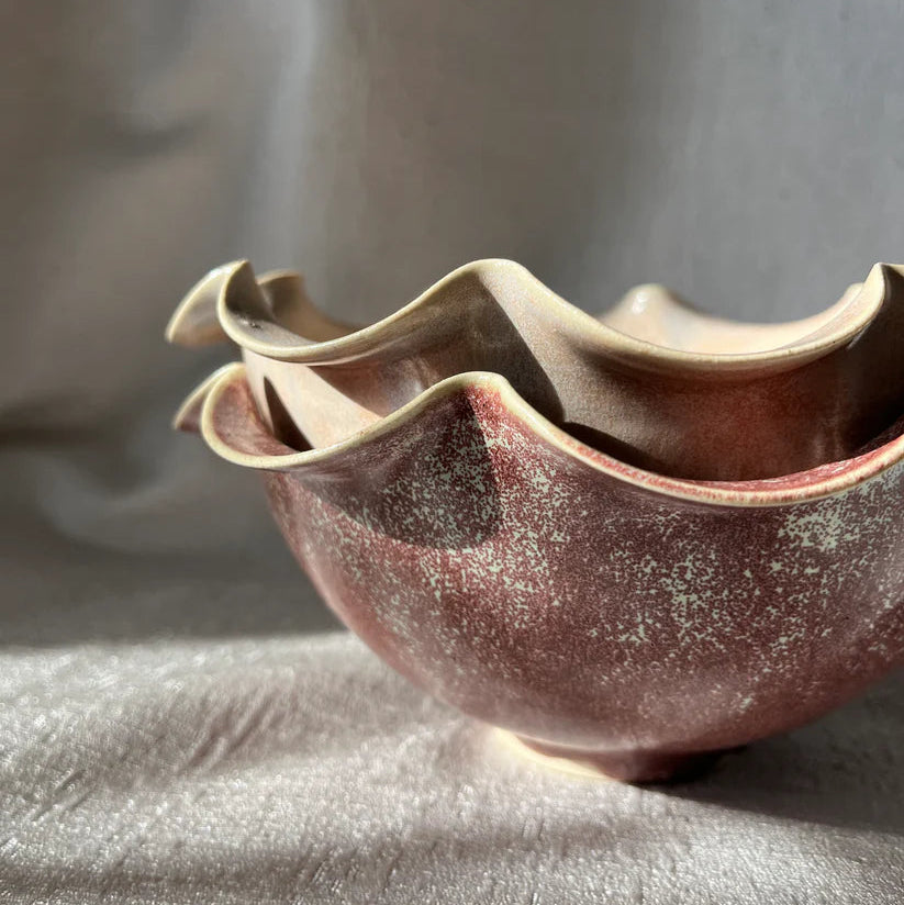 Ceramic bowl with wavy edge on a textured surface