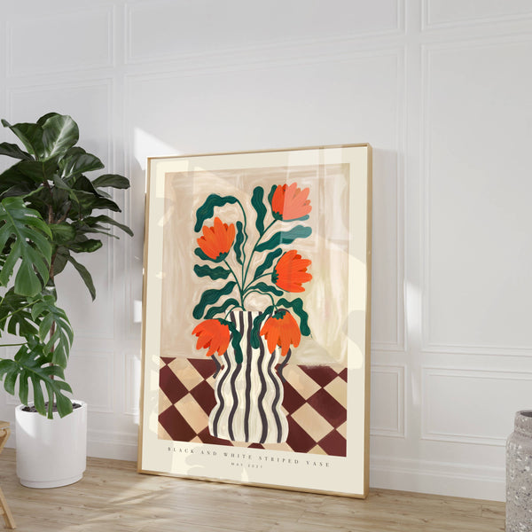 Framed artwork with orange flowers and a vase on a checkered pattern, placed in a room with a plant and vase.