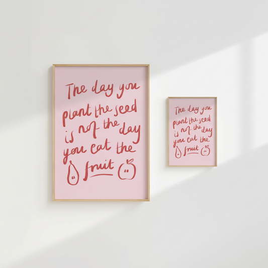 Framed pink poster with red text and illustrations on a white wall