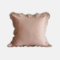 A square blush pink pillow with a scalloped edge and subtle vertical ribbed texture, shown against a plain light gray background.