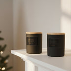 Two black candles with wooden lids on a striped fabric surface.