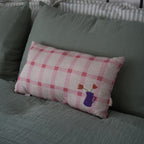 Nobodinoz pink tulip checkered throw cushion displayed on a bed with a green linen cover 