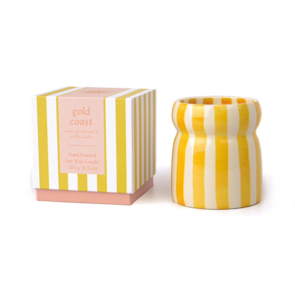 Yellow and white striped candle with matching striped box on a white background