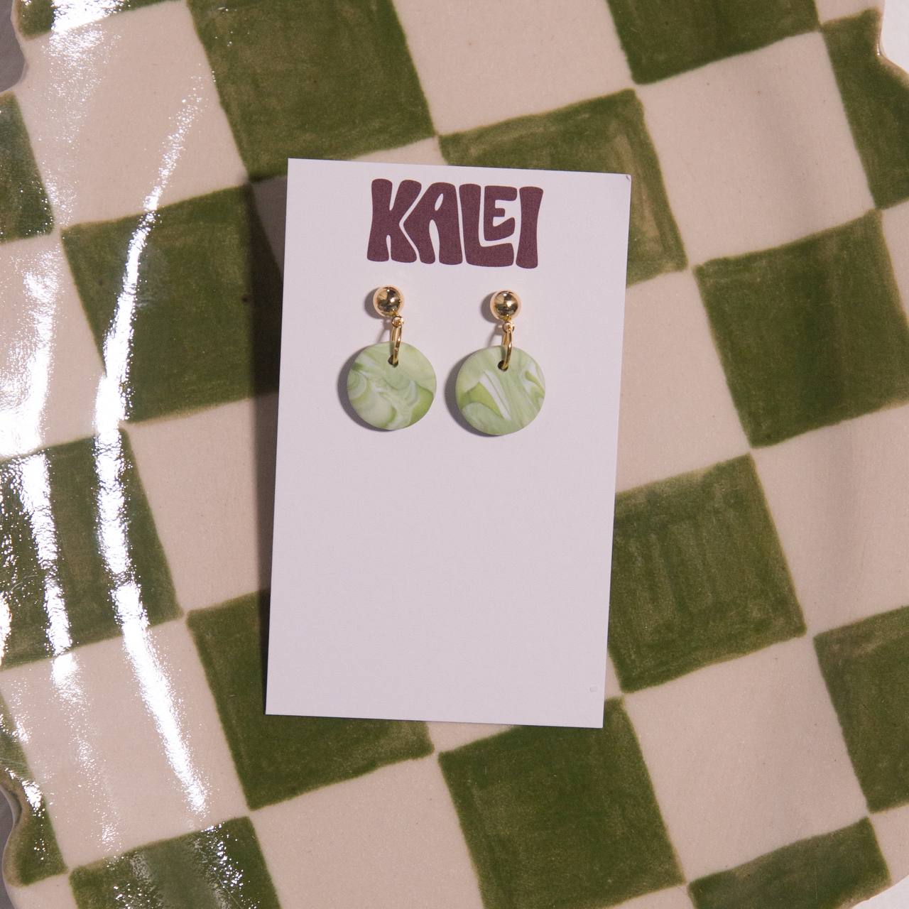 Green marbled earrings on a 'KALEI' branded card against a checkered background