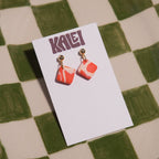Pair of earrings on a KALEI branded card against a checkered background