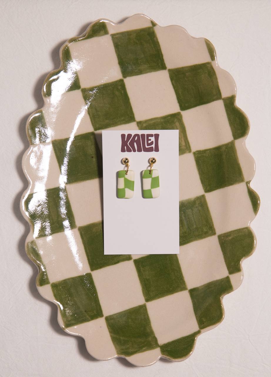 Green and white checkered earrings on a matching card with 'Kalei' branding, displayed on a green and white checkered stand.