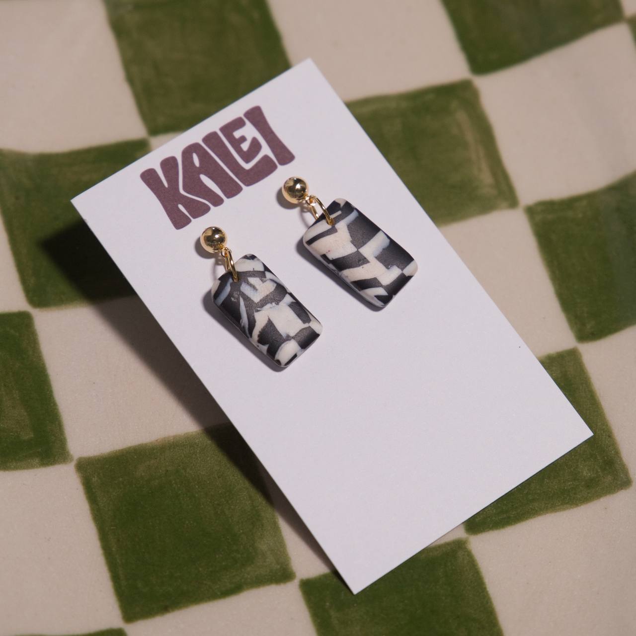 Pair of earrings on a KALEI branded card against a checkered background