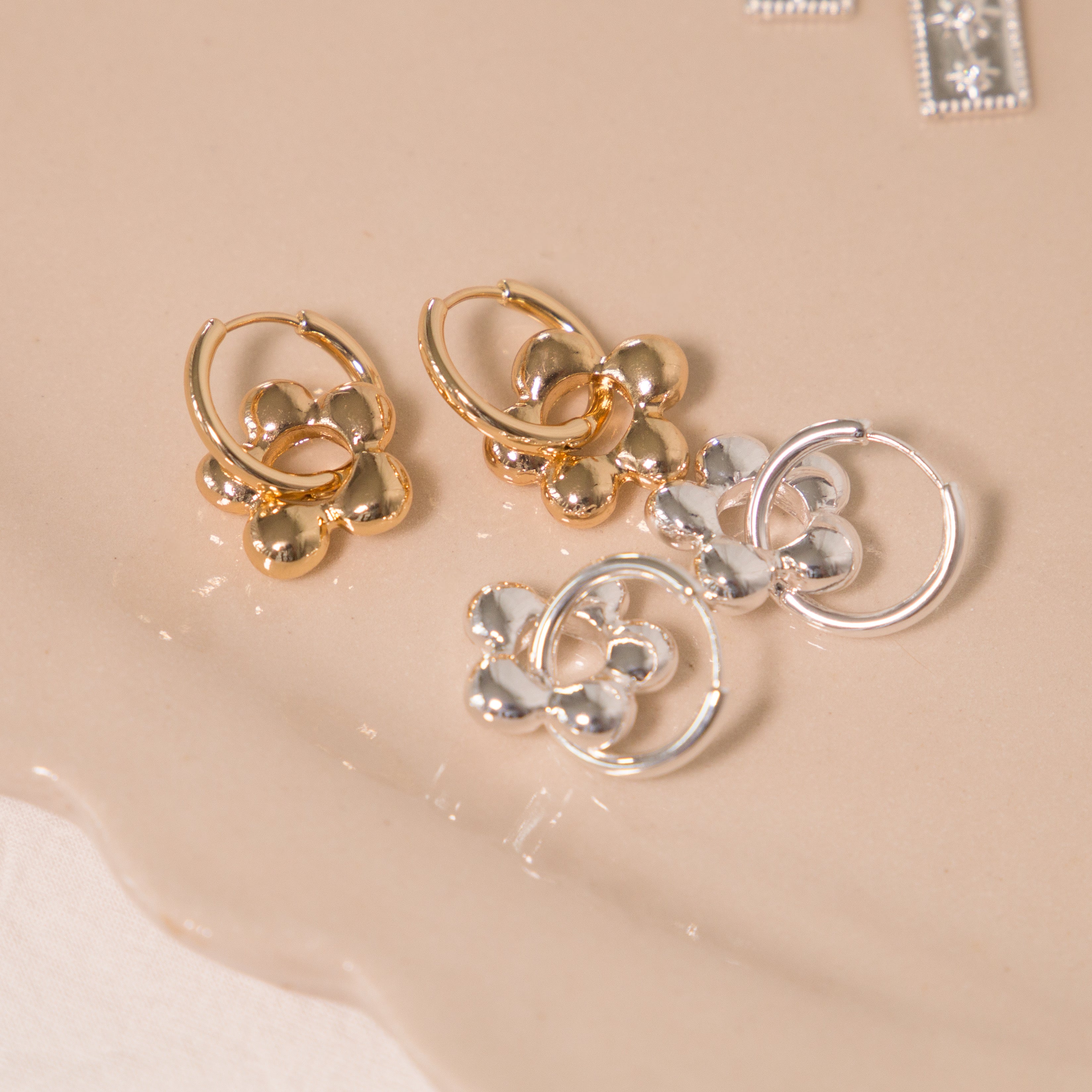 Pair of gold and silver hoop earrings on a beige surface