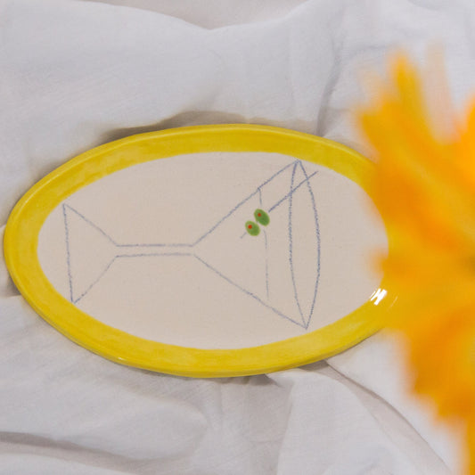 Yellow circular object on a white fabric background with a blurred sunflower in the foreground.