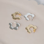 Four pairs of gold and silver earrings on a light gray background