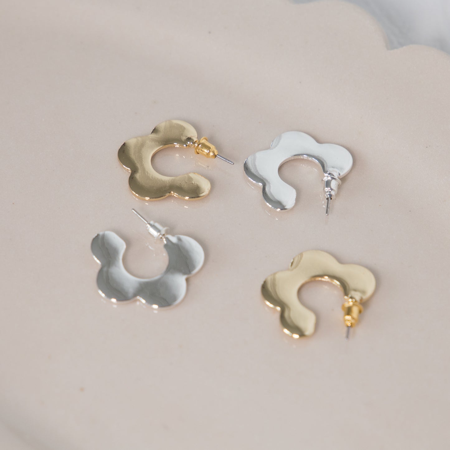 Four pairs of gold and silver earrings on a light gray background