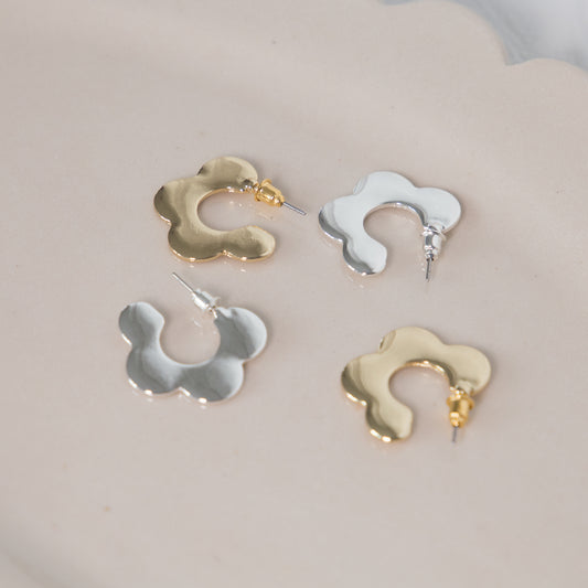 Four pairs of gold and silver earrings on a light gray background